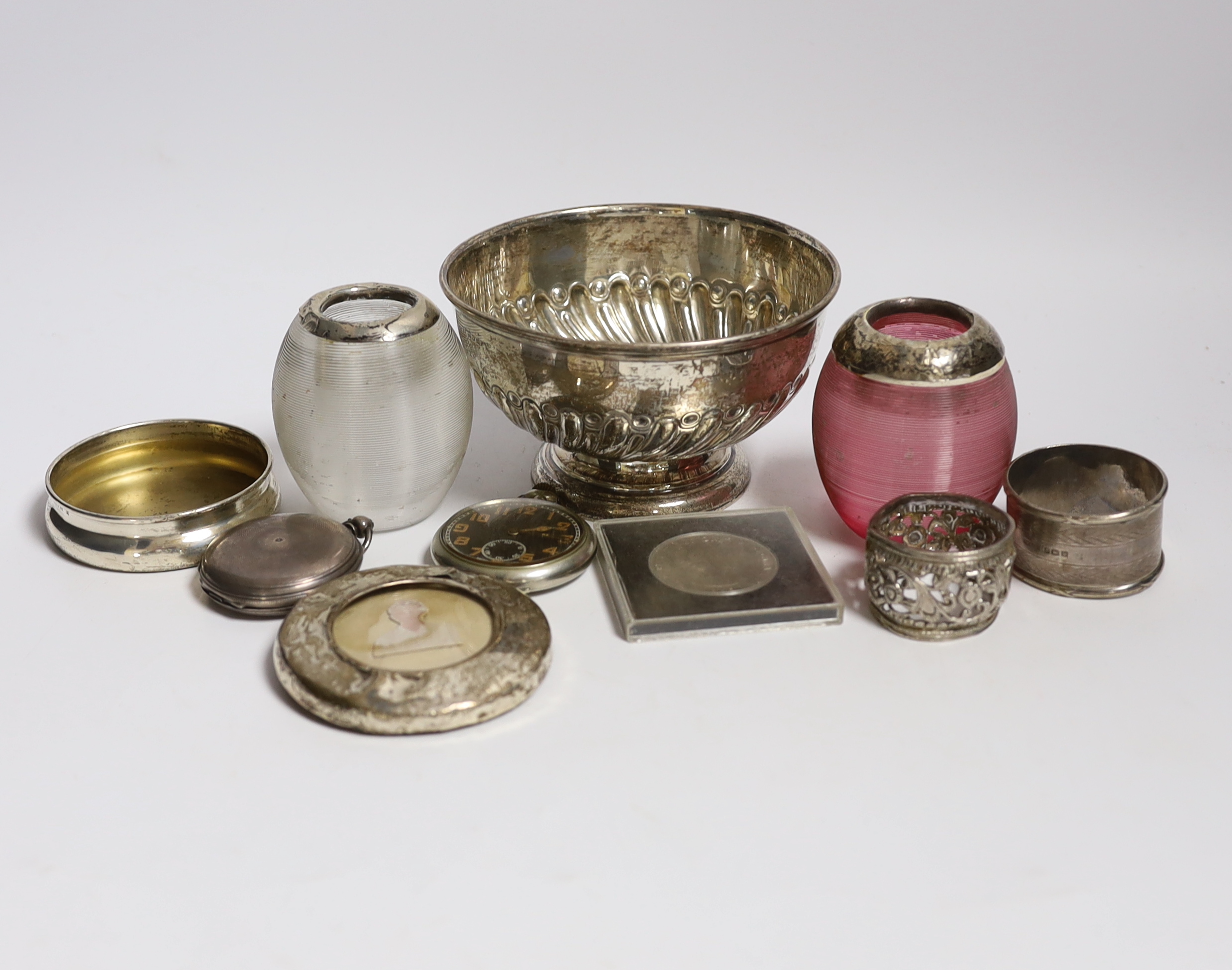 A collection of small silver, to include two mounted glass match strikes, one with cranberry glass, 71mm, a demi fluted bowl, photograph frame, napkin ring, lid and pocket watch, together with one other pocket watch, a c